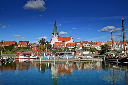 Porto di Roenne a Bornholm con chiesa e barche sul mare.