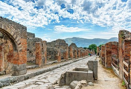 Strada lastricata tra rovine di Pompei sotto cielo nuvoloso.