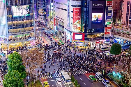 Folla attraversa Shibuya Crossing a Tokyo di notte con luci al neon.