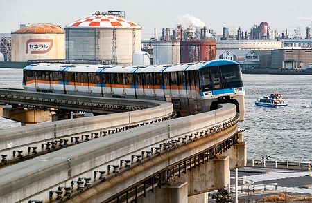 Treno Serie 1000 del Tokyo Monorail con sfondo della baia industriale di Tokyo.