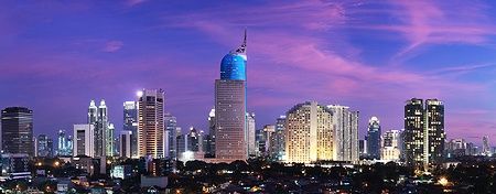 Skyline di Giacarta al tramonto con edifici illuminati.