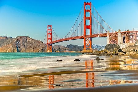 Golden Gate Bridge su un giorno di sole a San Francisco con riflesso sull'acqua.