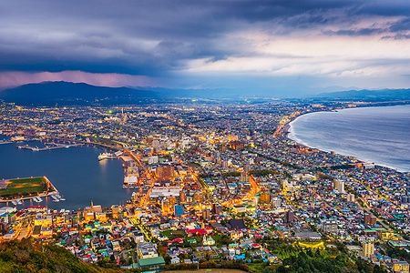 Skyline di Hakodate, Hokkaido, con luci al crepuscolo e costa visibile.