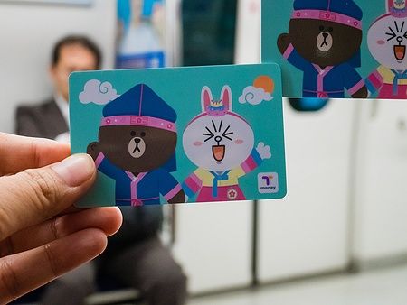 Mano che tiene una carta T-Money con personaggi di Line nel metro di Seoul.