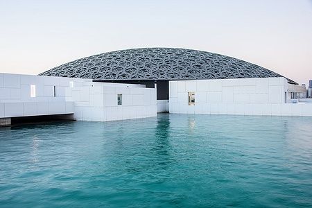 Il Louvre di Abu Dhabi con la sua cupola elaborata e riflessi sull'acqua.