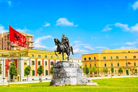 Statua equestre di Skanderbeg nella Piazza Scanderbeg a Tirana sotto un cielo blu.