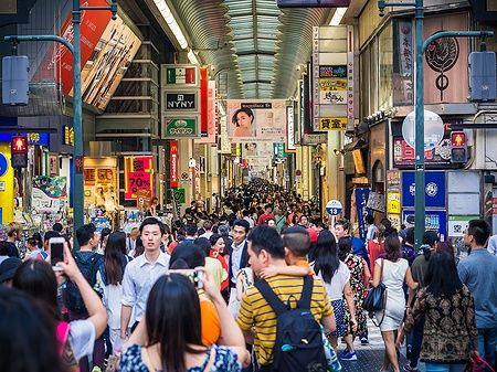 Folla di persone in una strada commerciale coperta a Osaka, Giappone.