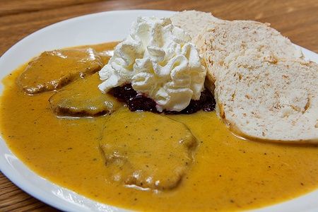 Piatto di svickova vegana con salsa cremosa e fette di pane.