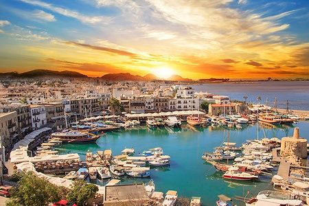 Vista della baia di Kyrenia con tramonto e barche nel porto.