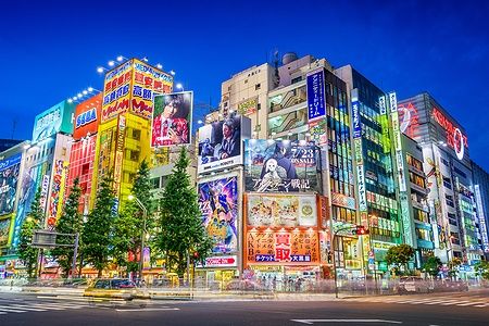 Insegne al neon ad Akihabara, Tokyo, di sera con folla nelle strade.