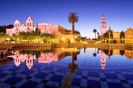 Veduta serale di Balboa Park a San Diego con riflessi d'acqua e luci accese.