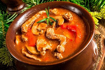 Ciotola di Beef Stroganoff con funghi e cipolle, decorata con rami di pino.
