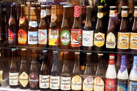 Bottiglie di birre belghe con varie etichette in una vetrina.
