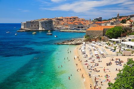 Vista panoramica del centro storico di Dubrovnik e della spiaggia affollata.