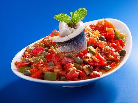 Piatto di insalata tunisina con peperoni, pesce marinato e capperi.