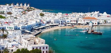 Panorama di Mykonos con case bianche e mulini a vento sul mare.