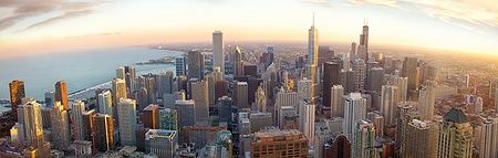 Panorama aereo di Chicago al tramonto con alti edifici e cielo colorato.