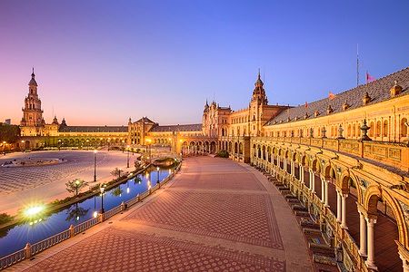 Plaza de España a Siviglia durante il tramonto con arcate e torre.