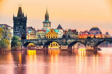 Il Ponte Carlo a Praga al tramonto con riflessi sul fiume e edifici storici.