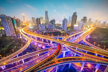 Superstrade illuminate di notte a Shanghai con grattacieli sullo sfondo.