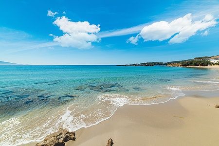 Le Bombarde in Alghero con acque turchesi e spiaggia dorata.