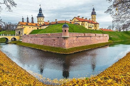 Castello di Nesvizh in Bielorussia, circondato da un fossato e foglie autunnali.