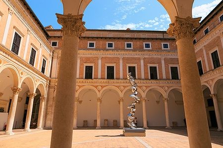 Cortile del Castello dei Duchi di Urbino con scultura moderna e colonne eleganti.