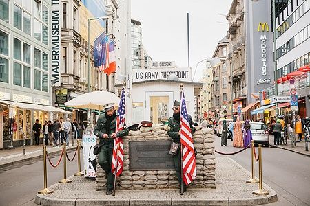 Checkpoint Charlie a Berlino con figure in costume militare e bandiere americane.