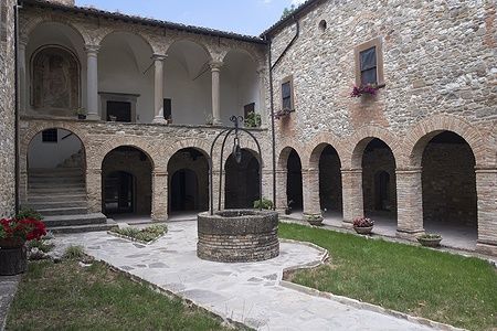 Cortile interno della chiesa di San Giovanni Battista a Carpegna con archi in pietra.