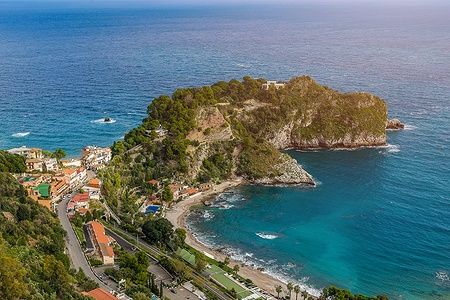 Mazzarò a Taormina con mare turchese e promontorio verde.