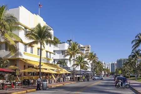 Hotel in stile Art Deco su Ocean Drive a Miami Beach con palme e persone.