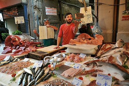 Venditore di street food con pesce e tonno al mercato di Palermo, Italia.