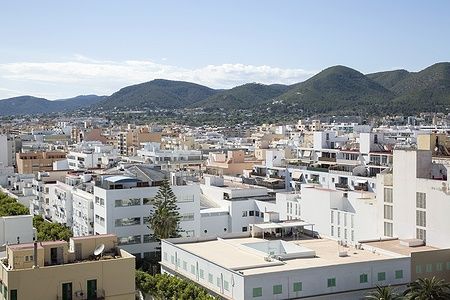 Vista panoramica della città di Ibiza con edifici e colline sullo sfondo.