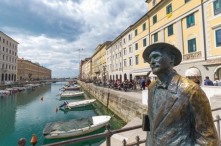Statua di James Joyce su Ponte Rosso a Trieste con canale e edifici storici.