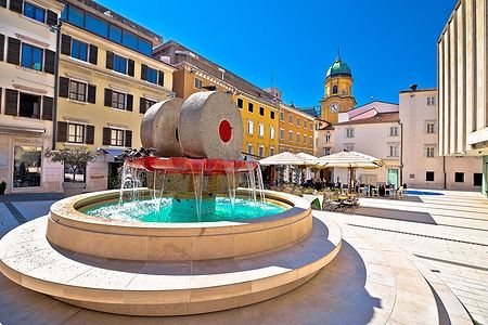 Vista della piazza e fontana di Rijeka con torre dell'orologio, Croazia.