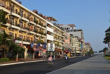 Strada di Sisowath Quay a Phnom Penh con edifici colorati e motociclette.