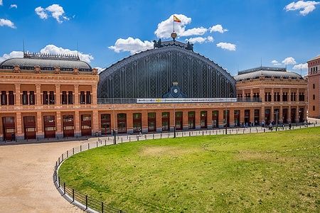 Stazione ferroviaria di Atocha a Madrid con struttura in vetro.