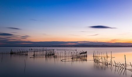 Tramonto sulla laguna Albufera a Valencia con reti da pesca sull'acqua calma.