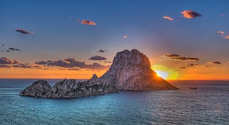 Tramonto su Es Vedrà a Ibiza con il cielo arancione e il mare calmo.