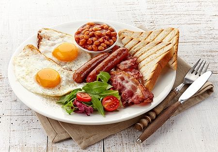 Piatto di English breakfast con uova, bacon, salsicce, fagioli e toast.