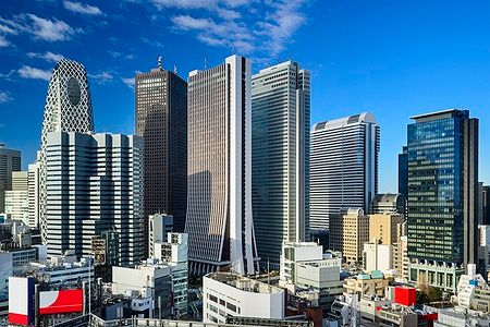 Skyline dei grattacieli di West Shinjuku a Tokyo sotto un cielo blu.