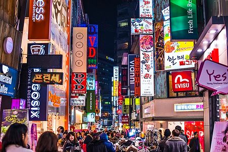 Insegne al neon di Myeong-Dong a Seoul, con folla di persone durante la notte.