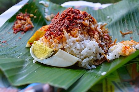 Nasi Lemak su foglia di banana con sambal, acciughe e arachidi.