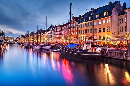 Il canale di Nyhavn a Copenhagen al crepuscolo con barche e case colorate riflettenti.