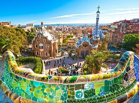 Vista del colorato Park Güell a Barcellona con persone e città sullo sfondo.