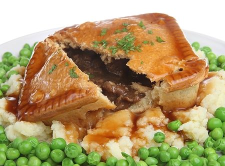 Beef steak pie con purè di patate, piselli e gravy su un piatto.