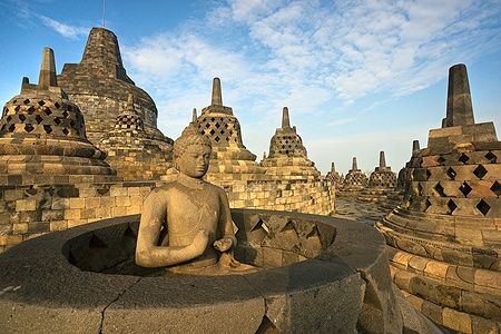 Tempio di Borobudur a Yogyakarta con statua di Buddha e stupa all'alba.