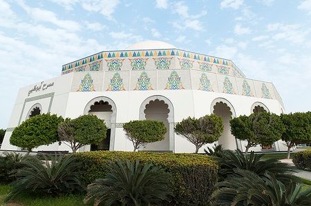 Edificio decorato al Heritage Village di Abu Dhabi, circondato da piante.