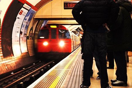 Treno della London Underground in arrivo su una piattaforma affollata.