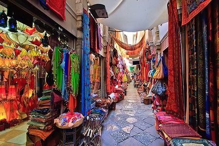 Mercato colorato a Granada con tessuti appesi e oggetti artigianali.